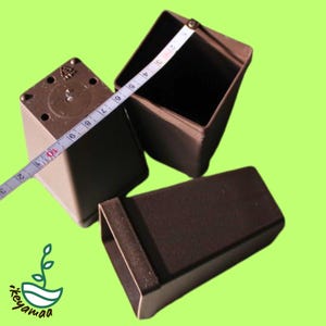 Pode incluir: Três vasos de plantas quadrados marrons são exibidos em um fundo verde. Uma fita métrica mostra que os vasos têm aproximadamente 10 cm de largura. Os vasos são feitos de um material durável e são adequados para várias plantas.