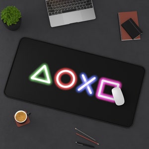 May include: Black gaming mouse mat with neon green, pink and blue symbols of a triangle, circle, X and square. The symbols are arranged in a row.