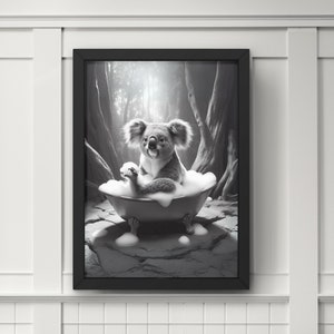 以下が含まれることがあります： 白黒の写真で、泡のあるバスタブの中にコアラが入っています。コアラは座ってカメラを見ています。写真は額縁に入っていて、白い壁に飾られています。