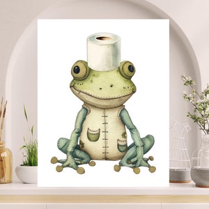 May include: A whimsical watercolor illustration of a frog wearing a toilet paper roll as a hat. The frog is light green with blue limbs and a cream-colored vest. The artwork has a soft, textured appearance, perfect for a nursery or bathroom decor.