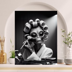 May include: A black and white photo of an alien wearing curlers and applying makeup with a brush.