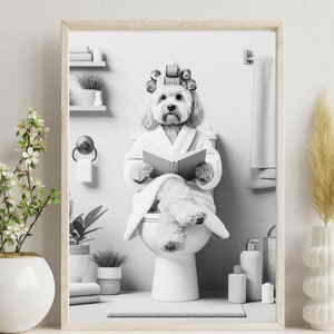 Peut inclure: Une photo en noir et blanc d'un chien assis sur des toilettes et lisant un livre. Le chien a des rouleaux dans les cheveux et porte une robe blanche. La photo est encadrée dans un simple cadre en bois.