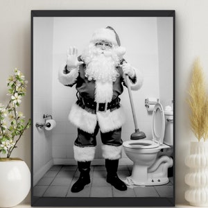 May include: A black and white photograph of Santa Claus in a bathroom, using a plunger to unclog a toilet. He is wearing a traditional Santa suit with a white beard and hat. The toilet is white and has a white seat. The bathroom is tiled and has a white sink and mirror.