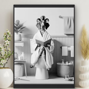 May include: A black and white photograph of a dog wearing a white bathrobe and hair rollers, sitting on a toilet and reading a book.