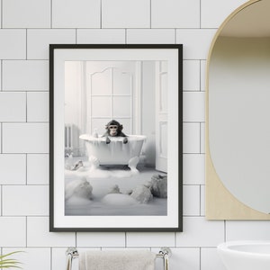 May include: A black and white photo of a monkey sitting in a white bathtub filled with bubbles. The monkey is looking at the camera. The photo is framed in a black frame.