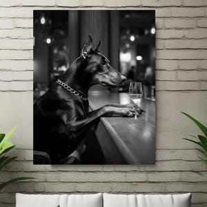 Peut inclure: Un chien Dobermann noir est assis au comptoir d'un bar avec un verre de vin. Le chien porte un collier en cha&icirc;ne argent&eacute;e et regarde le verre de vin.