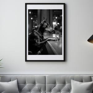 Peut inclure: Un chien Dobermann noir est assis au comptoir d'un bar, regardant un verre de vin. Le chien porte un collier en cha&icirc;ne argent&eacute;e.