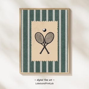 May include: A framed print featuring a tennis theme. The artwork showcases two crossed tennis rackets and a ball on a tan background, set against a green and white striped pattern. The frame is a light brown color. The text "digital fine art" and "LabelsandPrintLab" is at the bottom.