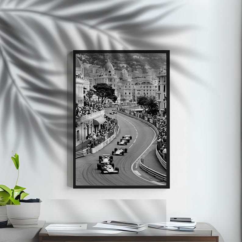 Puede incluir: Impresi&oacute;n enmarcada en blanco y negro de una carrera de F&oacute;rmula 1 en M&oacute;naco. La imagen muestra coches de carreras en una pista sinuosa, con espectadores y edificios al fondo. La impresi&oacute;n est&aacute; en un marco negro.