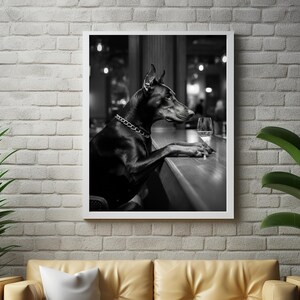Peut inclure: Un chien Dobermann noir est assis &agrave; un comptoir de bar, regardant un verre de vin. Le chien porte un collier en cha&icirc;ne argent&eacute;e. L'image est en noir et blanc.