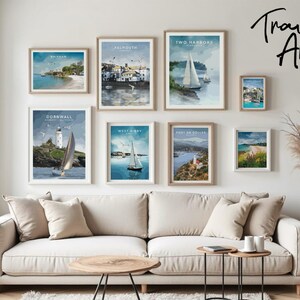 a cozy living room with a white sofa and a coffee table, adorned with framed pictures of coastal towns and sailboats. The pictures are arranged on the wall, creating a visually appealing display.