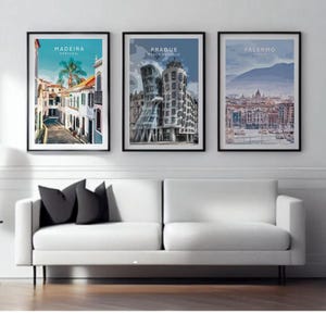 three framed pictures of different cities, including Madeira, Palermo, and Paderborn, displayed on a wall above a white sofa in a living room setting.