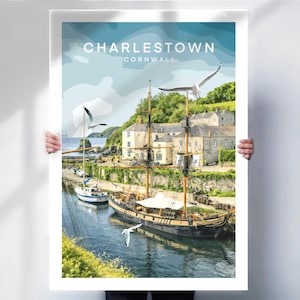May include: A poster featuring Charlestown, Cornwall, with a tall ship and seagulls. The artwork depicts a harbor scene with buildings, boats, and a blue sky. The text "Charlestown Cornwall" is at the top.