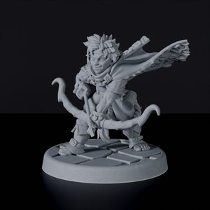 Puede incluir: Una miniatura de un arquero halfling impresa en 3D en gris, sosteniendo un arco y una flecha. El personaje lleva una capa con capucha y está de pie sobre una base circular.