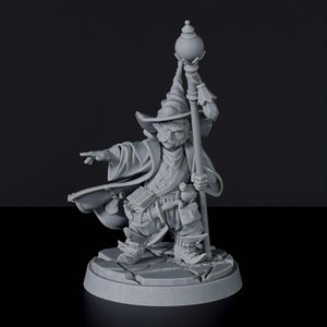 Peut inclure: Une figurine miniature grise et détaillée d'un sorcier avec un chapeau pointu, une longue barbe et un bâton. Le sorcier porte une longue robe et tient un bâton surmonté d'une sphère. La figurine est posée sur une base circulaire.