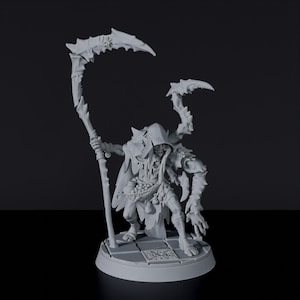 May include: A gray, detailed miniature figure of a creature with a hooded cloak, holding a scythe and a staff. The figure is standing on a circular base with a checkered pattern.