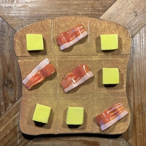 Handgjort keramiskt Tre-i-tac-toe-spel: Bacon vs. smörkonst
