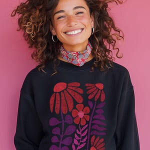 May include: A black sweatshirt with a colorful floral print. The flowers are red, pink, and purple and have a vintage, retro style.