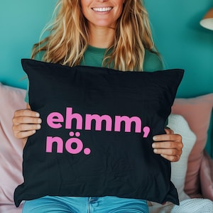 Könnte beinhalten: Schwarzes Kissen mit dem pinkfarbenen Text "ehmm, nö.". Das Kissen ist rechteckig und scheint aus einem weichen Stoff zu bestehen. Der Text ist mittig auf dem Kissen platziert.