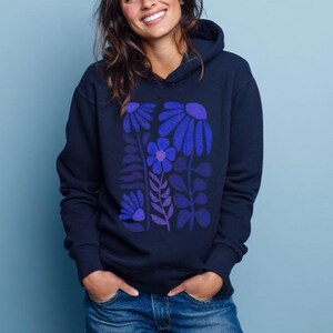 May include: A navy blue hooded sweatshirt featuring a graphic print of stylized flowers and leaves in shades of blue and purple. The hoodie has long sleeves, a front kangaroo pocket, and a hood with drawstrings, providing a casual look.