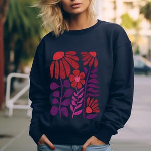May include: A navy blue sweatshirt with a colorful floral print. The print features red, pink, and purple flowers and leaves.