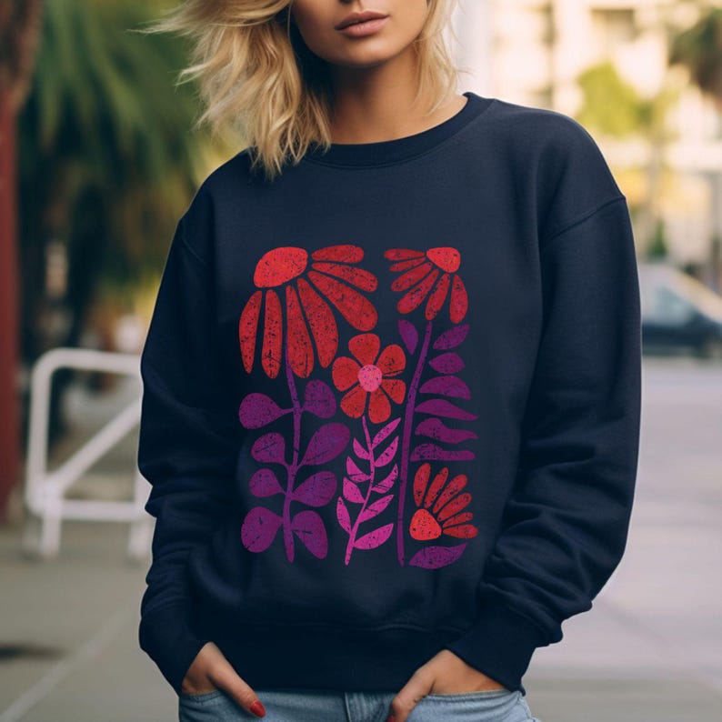 May include: A navy blue sweatshirt with a colorful floral print. The print features red, pink, and purple flowers and leaves.
