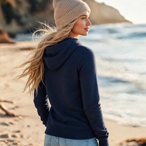 May include: A navy blue long-sleeved hooded sweatshirt with a drawstring hood and a ribbed hem, paired with a light beige knit beanie cap. The hoodie features a solid color design with long sleeves and a standard fit, worn with light blue denim jeans.