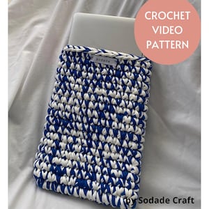 Peut inclure: Une housse d'ordinateur portable crochetée bleue et blanche avec un motif texturé. La housse est faite de fil épais et porte une petite étiquette indiquant "sodade". L'image comprend également le texte "CROCHET VIDEO PATTERN" et "by Sodade Craft".