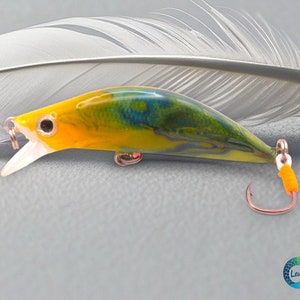 May include: A yellow, green and blue fishing lure with a white mouth and black eyes. The lure has a single hook and is designed to resemble a small fish.