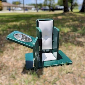 May include: A green wooden pet carrier with a stainless steel bowl and a white cushion. The carrier has a hinged door and a latch. The bowl is on a side table attached to the carrier.