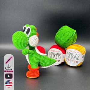 Könnte beinhalten: Eine handgefertigte grüne, rote, weiße und orangefarbene Yoshi-Figur aus Häkelarbeit steht neben drei Knäueln Garn. Die Garnfarben sind grün, rot und gelb. Die Figur hat große weiße Augen und orangefarbene Stiefel.