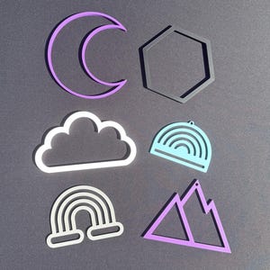 May include: A collection of six flat, geometric and nature-themed shapes including a purple crescent moon, a dark gray hexagon, a white cloud, a light blue semi-circular rainbow, a white arched rainbow, and a purple mountain range outline.
