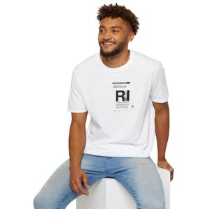 Könnte beinhalten: Ein weißes T-Shirt mit einem schwarzen Grafikdruck, auf dem "RUBICON III RESEARCH INSTITUTE" und "RI" in großer Schrift stehen.