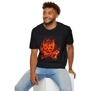 May include: Black t-shirt featuring a fiery skull and crossbones design. The graphic is rendered in shades of red, orange, and yellow, creating a burning effect. The shirt is a classic crew neck style.