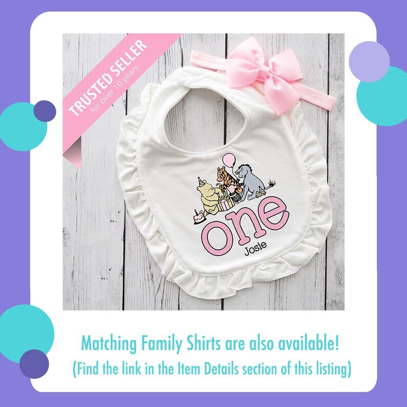 Puede incluir: Babero blanco para beb&eacute; con diadema de lazo rosa. El babero presenta un ribete de volantes y un gr&aacute;fico de personajes de Winnie the Pooh con la palabra "one" y el nombre "Josie". El texto "TRUSTED SELLER for over 10 years" tambi&eacute;n es visible.