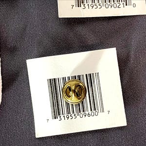 May include: A small, gold-colored lapel pin with a circular design is displayed on a white tag with a barcode and the number "31955 09600 7". The pin is set against a dark gray textured background.