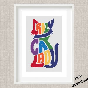 May include: Framed cross-stitch art featuring a colorful cat silhouette. The cat shape is formed by the words "CRAZY CAT LADY" in rainbow hues. The artwork is in a white frame, with "PDF download" text in the bottom right corner.
