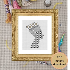 May include: A black and white cross-stitch pattern of a woman's profile wearing a patterned headdress. The pattern is framed in a gold frame.
