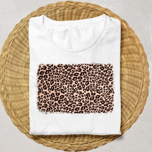 May include: White t-shirt with a pink and brown leopard print design.