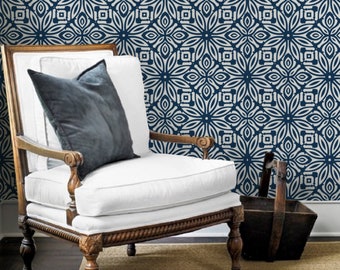 May include: A white armchair with a dark gray pillow sits in front of a wall covered in blue and white patterned wallpaper. The wallpaper features a repeating geometric design.