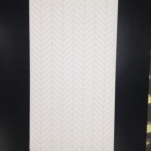 May include: A white background with a subtle herringbone pattern in a light beige color.