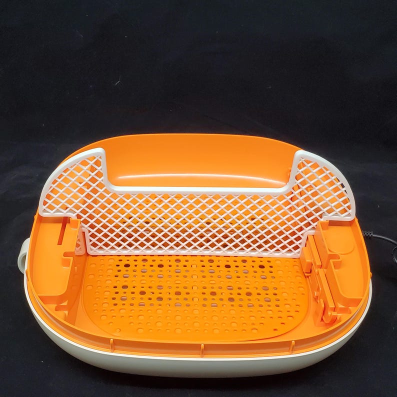 May include: An orange and white plastic foot bath with a white mesh insert. The foot bath has a textured bottom and a white lid.