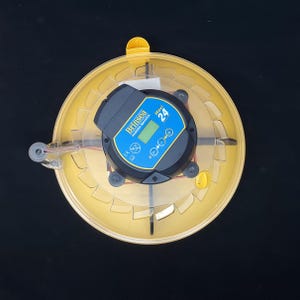 Puede incluir: Una incubadora de huevos autom&aacute;tica Brinsea Mini 24 amarilla con una pantalla digital y un panel de control. La incubadora tiene una tapa transparente y una base giratoria.