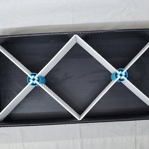 May include: A black storage box with white dividers and blue plastic connectors. The box is divided into six compartments.