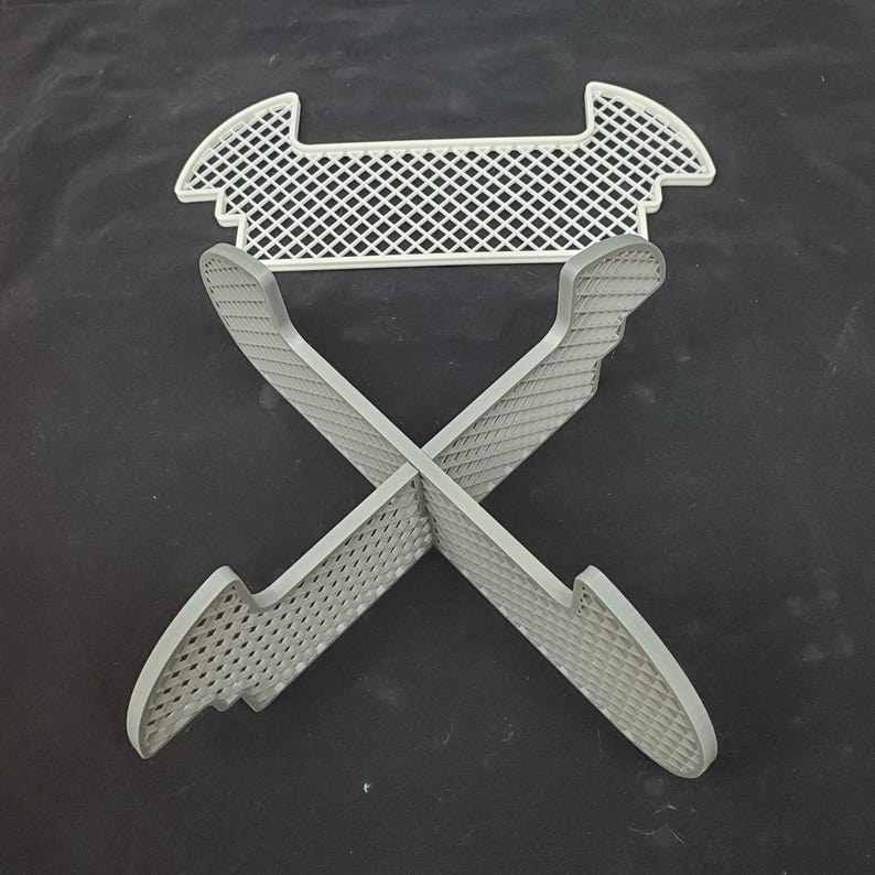 May include: A white plastic stand with a grid pattern. The stand is designed to hold items upright and has four legs that form an X shape. The stand is made of a lightweight material and is easy to assemble.