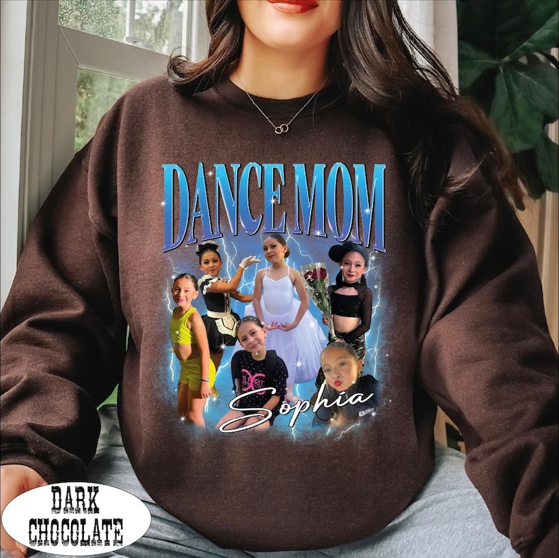May include: Dark chocolate brown sweatshirt with a graphic that says "DANCE MOM" in blue and white. The graphic features a photo of several young girls in dance attire, with the name "Sophia" in cursive. The words "DARK CHOCOLATE" are at the bottom.