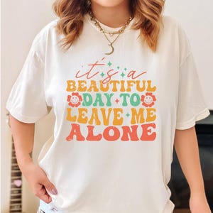 a woman wearing a t - shirt that says it's a beautiful day to