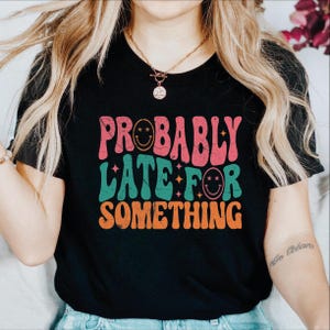 a woman wearing a black shirt that says probably later something