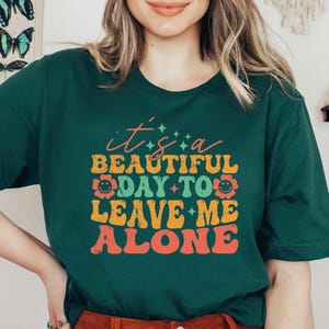 a woman wearing a green shirt that says it's a beautiful day to leave