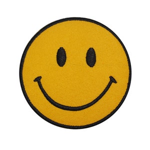 Op de afbeelding: Een gele smiley-patch met zwarte geborduurde details. De patch heeft een klassiek smiley-gezicht met zwarte ogen en een gebogen zwarte mond. De patch is rond en heeft een zwarte rand.